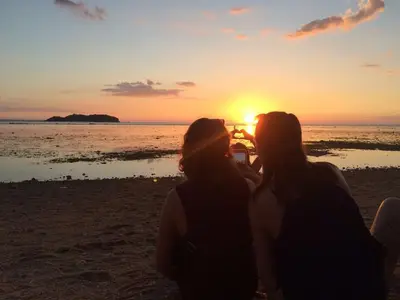 A couple taking a photo against a golden sunset on the beach