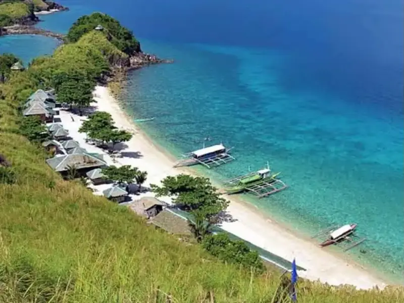 Aerial view of Sambawan Island's beachfront huts and outrigger boats along the white-sand shore