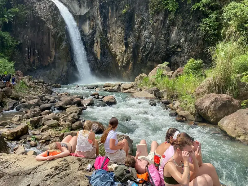 Guests resting on the rocks below a waterfall that pours into a rocky canyon on Biliran Island