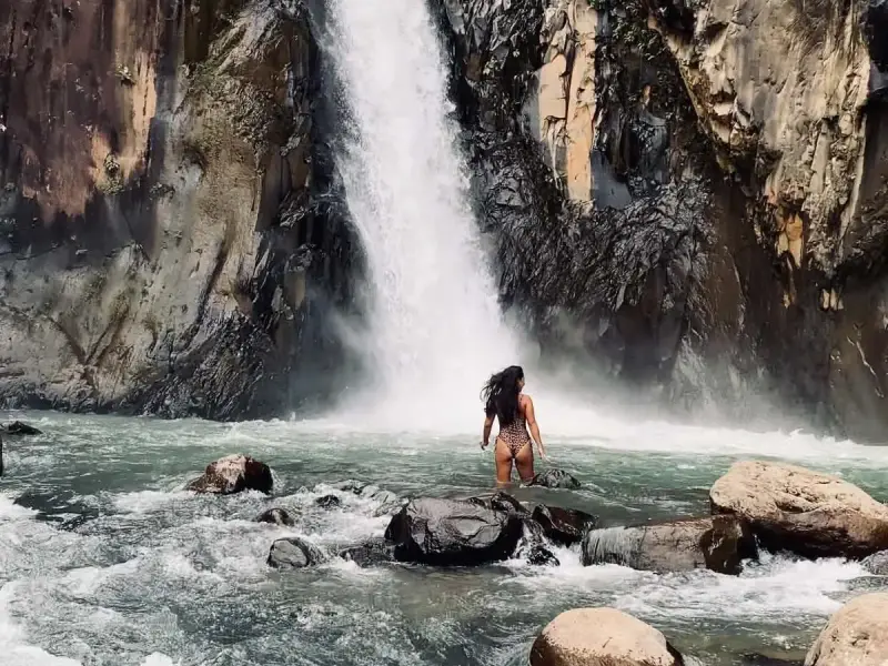 A guest wading through the river towards a canyon waterfall on Biliran Island