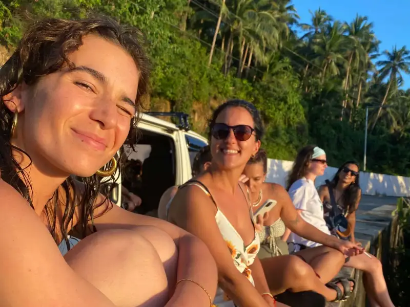 Guests relaxing on a wall beside the tour van at golden hour