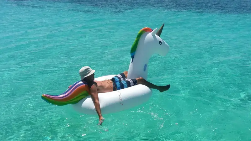 A guest floating on a unicorn inflatable in turquoise water off Lamanoc Island