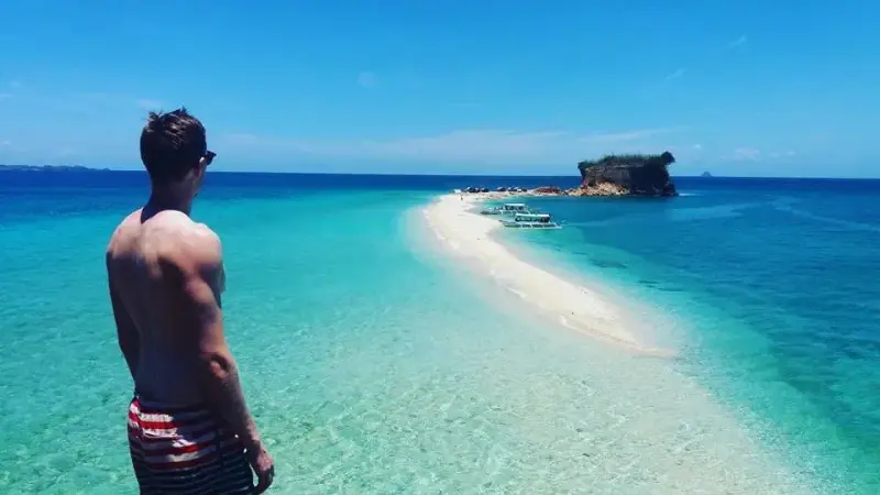 A guest looking out over Lamanoc's white sandbar stretching towards a rocky islet