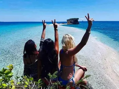 Three friends throwing peace signs on a turquoise sandbar at Lamanoc Island