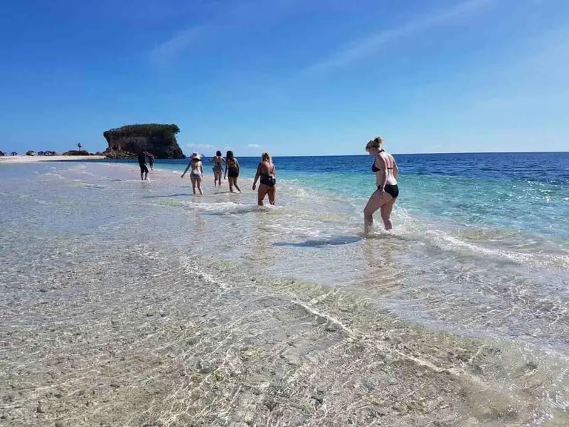 Guests wading through the shallows along the sandbar at Lamanoc Island