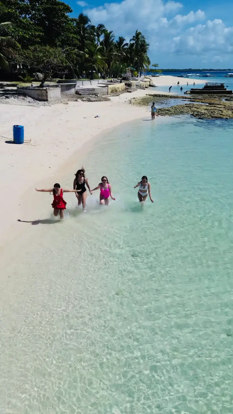 Guests running into the clear shallows off Virgin Island's white beach
